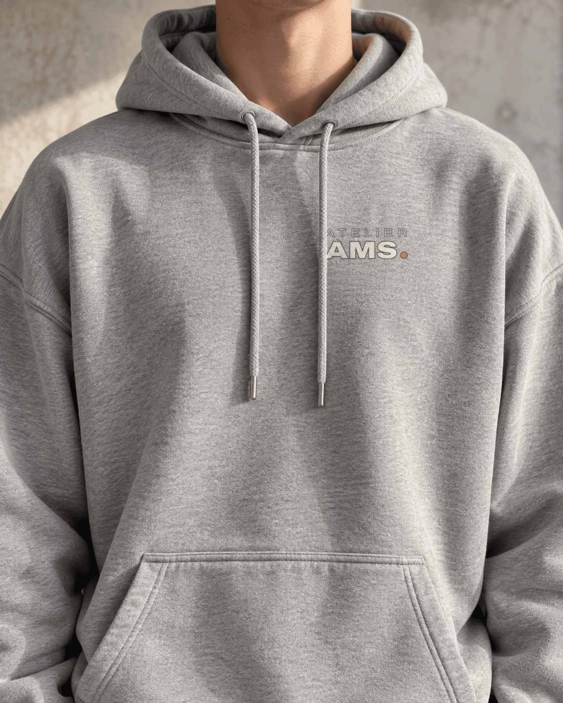 Nærbillede af brystet på en grå hoodie med Atelier AMS-mærket